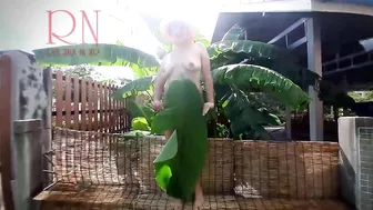 Rural striptease. Country girl dancing in the yard of her house Rustic striptease with banana leaf