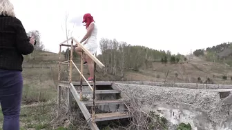 Behind the scenes. A girl with a big ass in a short dress makes an erotic photo session outdoors.