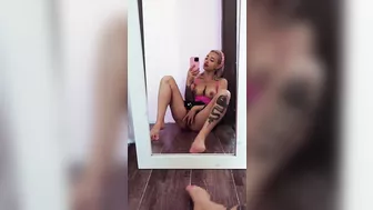 A busty beauty sits in front of a mirror and caresses her excited pussy.