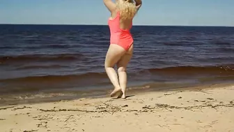 Juicy MILF in a pink swimsuit, on the beach